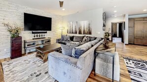 A modern living room with a flat-screen TV, grey sofa, wooden coffee table, and a ceiling fan. - Gondola Vista 4 Bedroom Villa w/ Hot Tub (South Lake Tahoe)