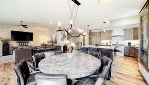 A modern kitchen with a central island, built-in appliances, and a dining area with a round table and leather chairs. - Gondola Vista 4 Bedroom Villa w/ Hot Tub (South Lake Tahoe)