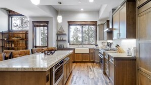 Una cocina moderna con armarios de madera, una isla de mármol y un ventanal con vistas a árboles.