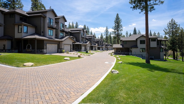 Un quartier résidentiel avec des maisons modernes, des allées pavées et des pelouses bien entretenues.