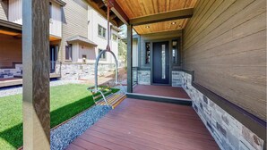 Un espace extérieur abrité, doté d’une terrasse en bois, d’un banc et d’un mur en pierre.
