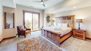 Ein Schlafzimmer mit einem großen Bett, einem Sessel, einem Nachttisch aus Holz und einem Deckenventilator.