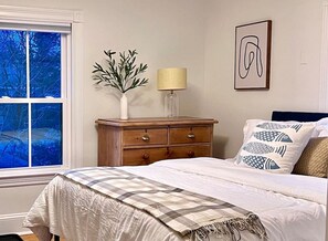 Une chambre à coucher avec un lit, une commode, une lampe, un vase et un tableau encadré au mur.