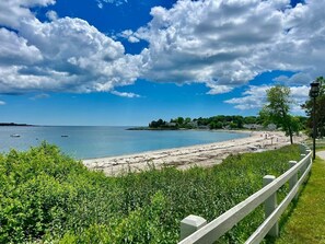 A coastal beach with a wooden fence, clear sky, and calm sea.