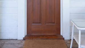 A wooden front door with a peephole and a small window above it.
