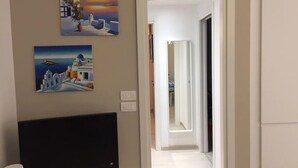 A hallway with a TV, paintings, and a door leading to another room. - Bright, renovated apartment with two bedrooms and parking space - 300m from the sea (Grado)