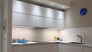 A modern kitchen with white cabinets, a stainless steel sink, and overhead lighting. - Bright, renovated apartment with two bedrooms and parking space - 300m from the sea (Grado)