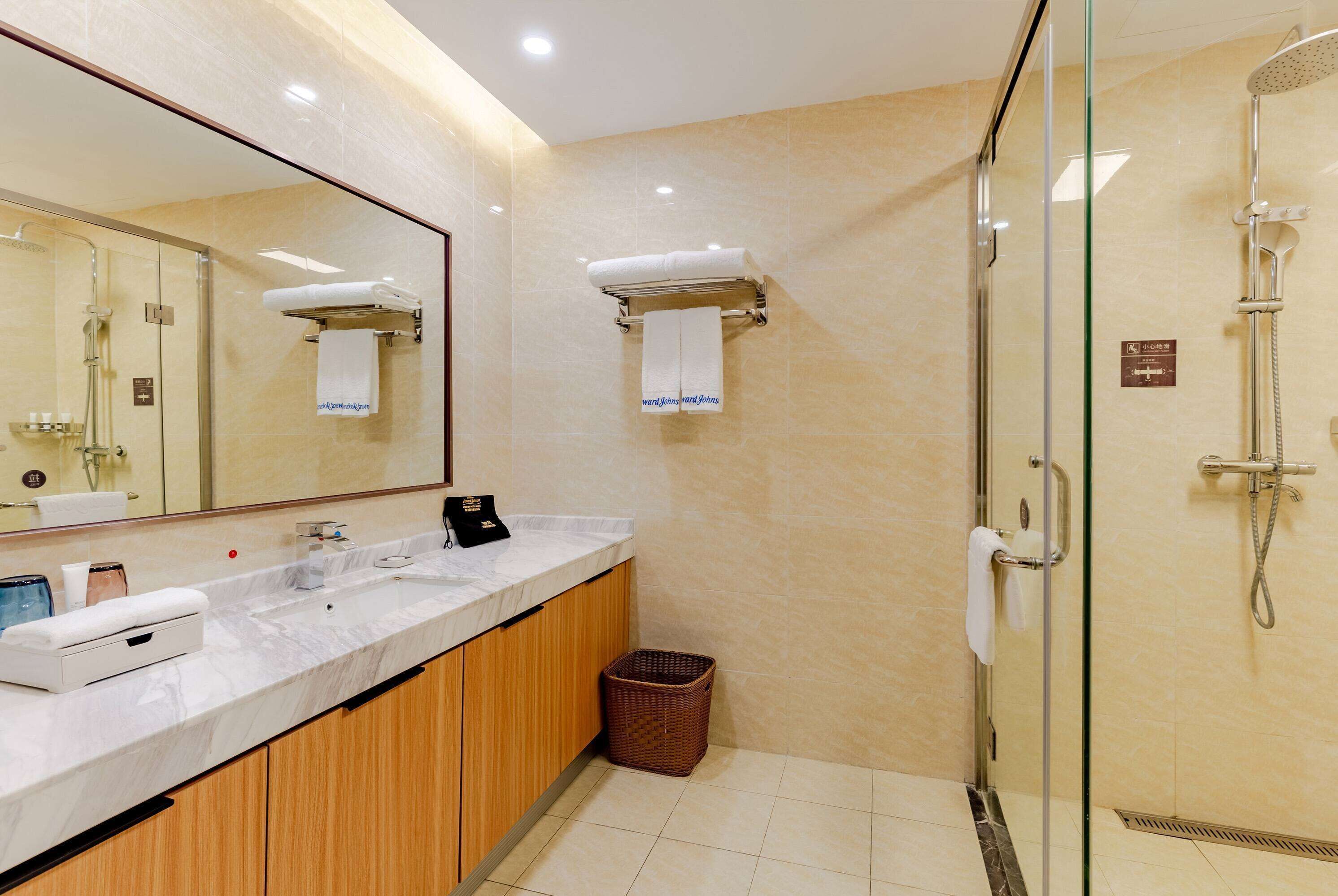 Un baño moderno con ducha de vidrio, encimera de mármol y armarios de madera.