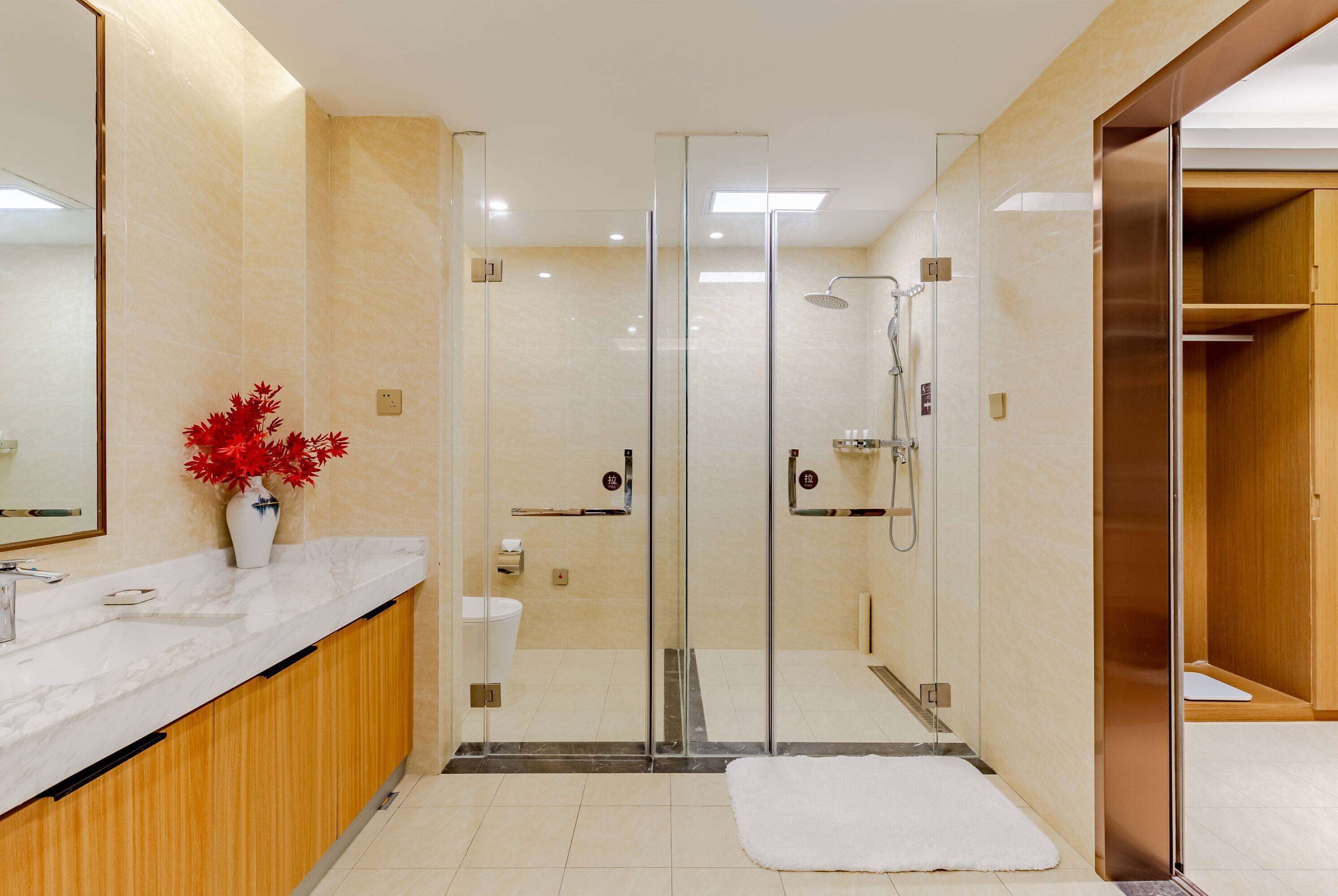 A modern bathroom with a glass-enclosed shower, a white sink with a marble countertop, and a wooden vanity.