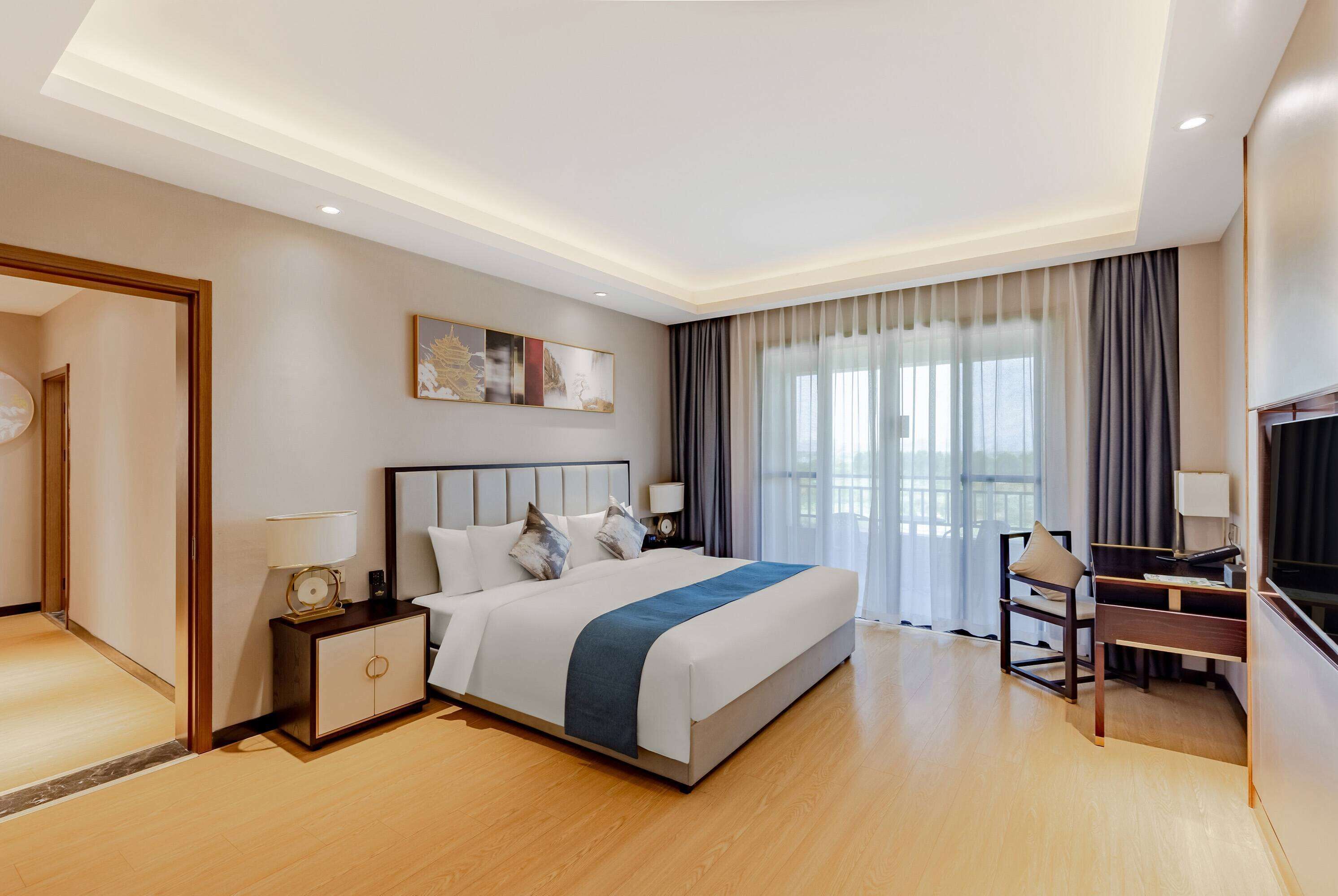 A modern hotel room with a large bed, bedside tables, a desk, and a TV.