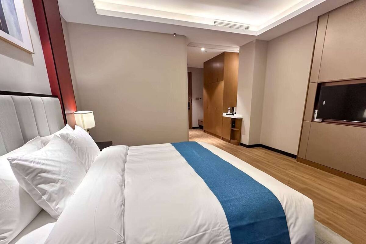 Une chambre d’hôtel avec un lit, une télévision, un bureau et une salle de bain que l’on aperçoit à l’arrière-plan.