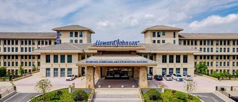 L’entrée de l’hôtel Howard Johnson Lakeview à Hualibai, avec un ciel dégagé, un escalier central et plusieurs voitures garées.