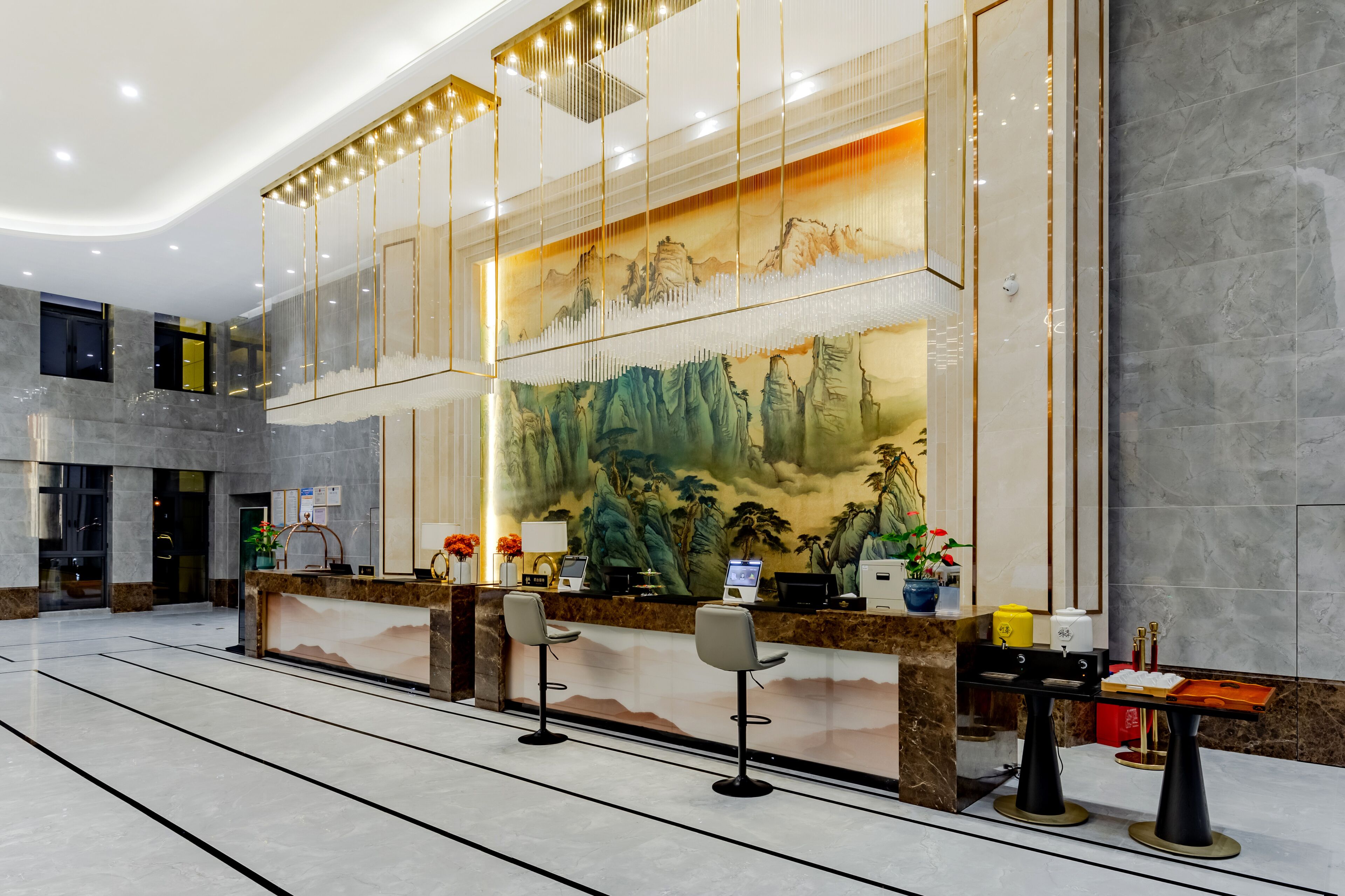 En moderne lobby med reception, to barstole og et stort bjergmotiv.