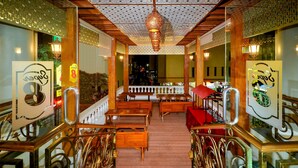 A restaurant with wooden tables and chairs, a staircase, and decorative lighting. - Super 8 By Wyndham Solo Indonesia (Surakarta)
