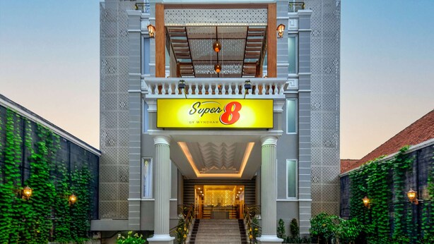 A hotel entrance with a prominent sign reading "Super 8" and a balcony with decorative railings. - Super 8 By Wyndham Solo Indonesia (Surakarta)