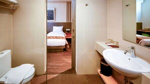 A hotel bathroom with a white sink, a toilet, and a shower area. - Super 8 By Wyndham Solo Indonesia (Surakarta)