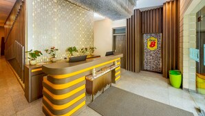 A reception area with a modern design, featuring a counter with a striped pattern, a decorative wall, and a sign indicating the location. - Super 8 By Wyndham Solo Indonesia (Surakarta)
