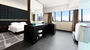 A modern hotel room with a large bed, a vanity with a mirror, a desk, and a view of the city through large windows. - Wingate By Wyndham Wuhan Optics Valley (Wuhan)