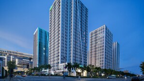 A high-rise building with a modern architectural design, featuring multiple floors and a prominent central tower. - Wingate By Wyndham Wuhan Optics Valley (Wuhan)