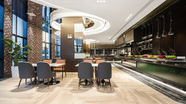 A modern dining area with a central table, chairs, and a decorative water feature. - Wingate By Wyndham Wuhan Optics Valley (Wuhan)