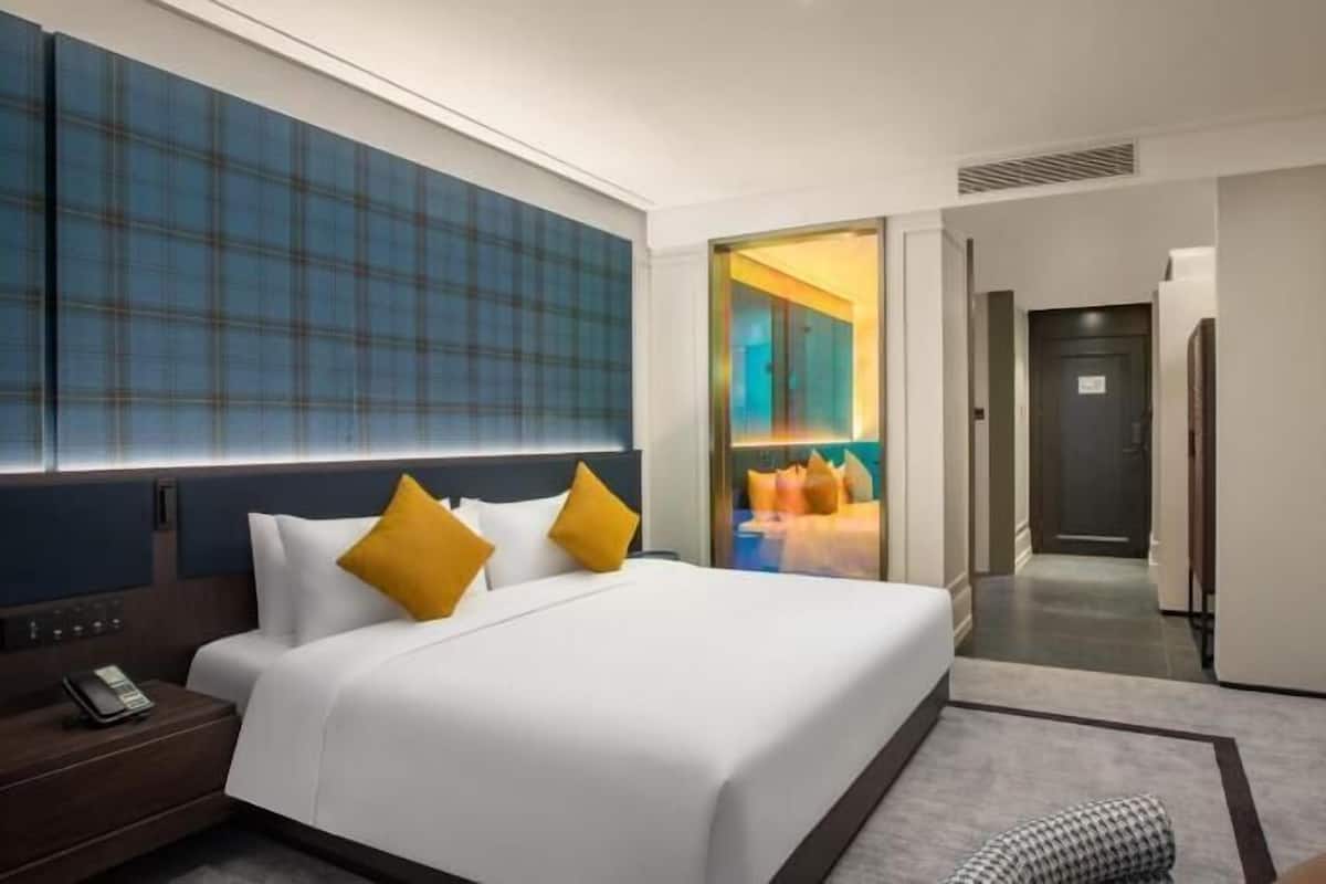 Ett hotellrum med en stor säng, en telefon vid sängen, en platt-TV och utsikt över korridoren.