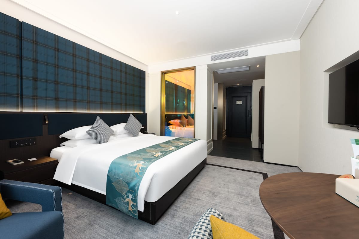 Ett modernt hotellrum med en stor säng, sängbord, ett skrivbord och en TV.