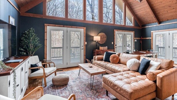 A spacious living room with a high ceiling, large windows, a fireplace, and a cozy seating area. - Spacious Mountain Cabin for 8 (Deep Gap, Watauga County)