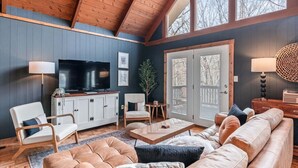 A cozy living room with a TV, seating, and a large window. - Spacious Mountain Cabin for 8 (Deep Gap, Watauga County)