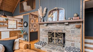 A cozy living room with a stone fireplace, wooden beams, and a comfortable sofa. - Spacious Mountain Cabin for 8 (Deep Gap, Watauga County)