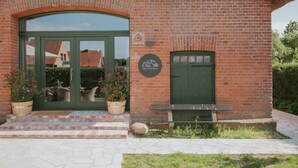 Un edificio de ladrillo con una puerta verde y un banco en el exterior.