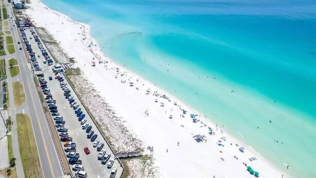An aerial view of a beach with a parking lot and beachgoers. - Modern Coastal 2BR: Walk to Beach, Pool at Back Door (Destin)