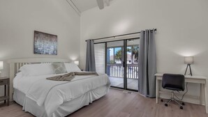 A bedroom with a bed, a desk, a chair, a ceiling fan, and a balcony with a view. - Modern Coastal 2BR: Walk to Beach, Pool at Back Door (Destin)