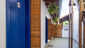 A corridor with blue doors, a wooden fence, and a tiled floor. - Pousada Recanto da Mata (Porto Seguro)