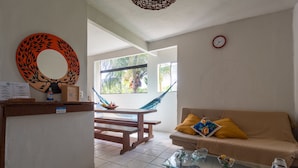 A living room with a sofa, coffee table, and a hammock. - Pousada Recanto da Mata (Porto Seguro)