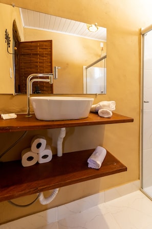 A bathroom with a wooden vanity, a white sink, and a mirror above it.