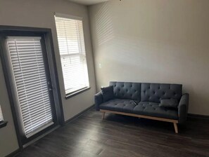 Relax in this serene space with a tufted sofa and two windows offering ample natural light.