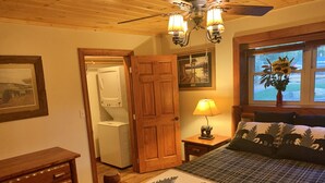 A bedroom with a bed, a nightstand with a lamp, a dresser, a wooden door, and a window with a view of the outdoors. - BEARADISE 1 - Five Min Walk To Downtown Banner Elk (Banner Elk)