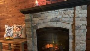 A stone fireplace with a lit fire, wooden benches, and decorative pillows. - BEARADISE 1 - Five Min Walk To Downtown Banner Elk (Banner Elk)