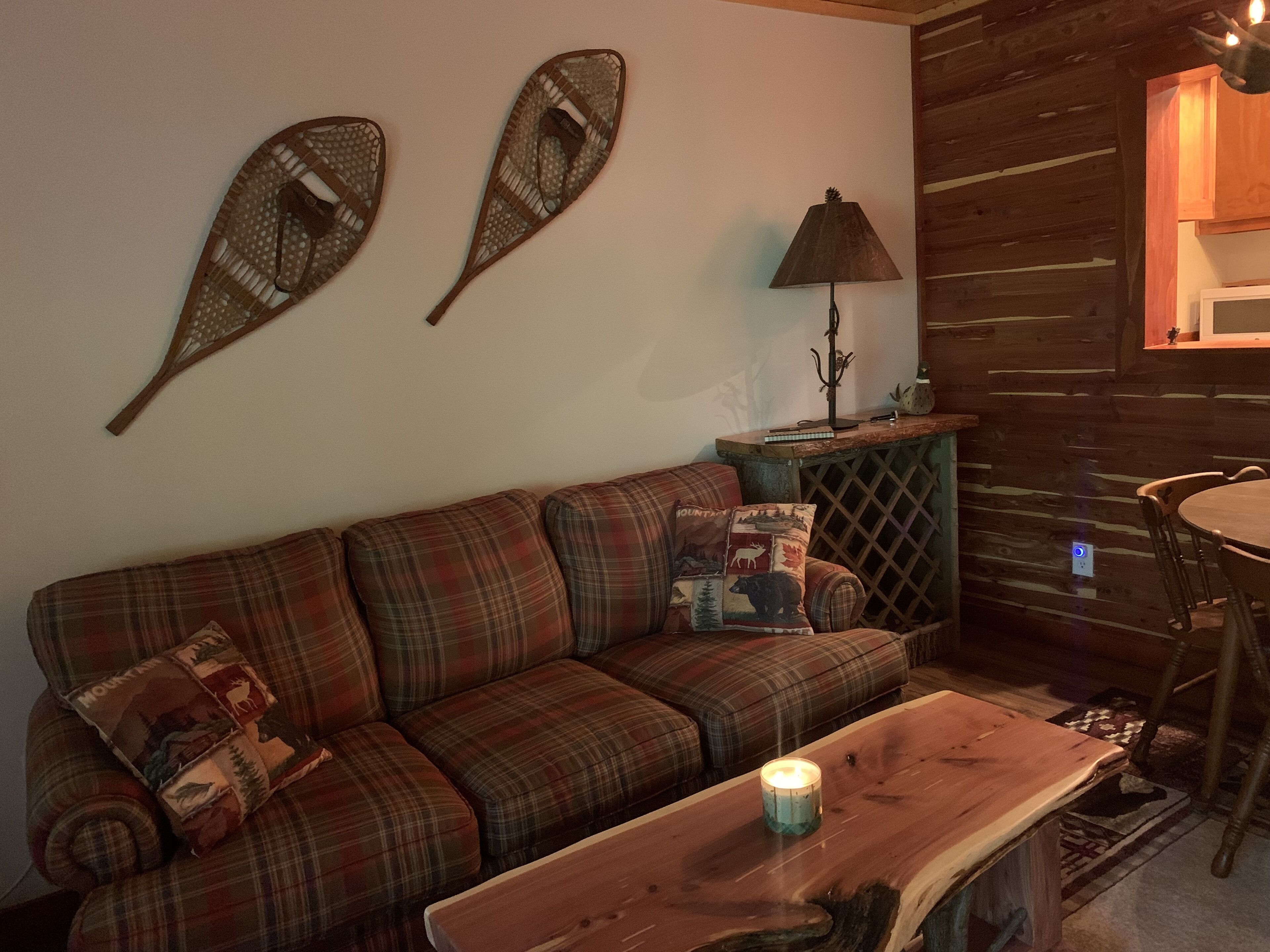 Un salon chaleureux avec un canapé à carreaux, une table basse en bois et des coussins décoratifs.