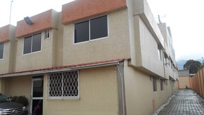 Un edificio residencial de varios pisos con techo plano, ventanas amplias y un camino de entrada pavimentado.