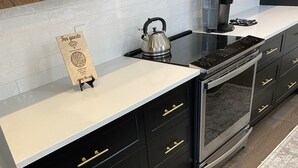 Eine moderne Küche mit schwarzen Schränken, einem Edelstahlkocher, einer Kaffeemaschine und einem eingebauten Backofen.
