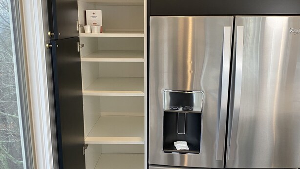 Ein Edelstahl-Kühlschrank mit Wasserspender, einem schwarzen Oberteil und einem weißen Unterschrank.