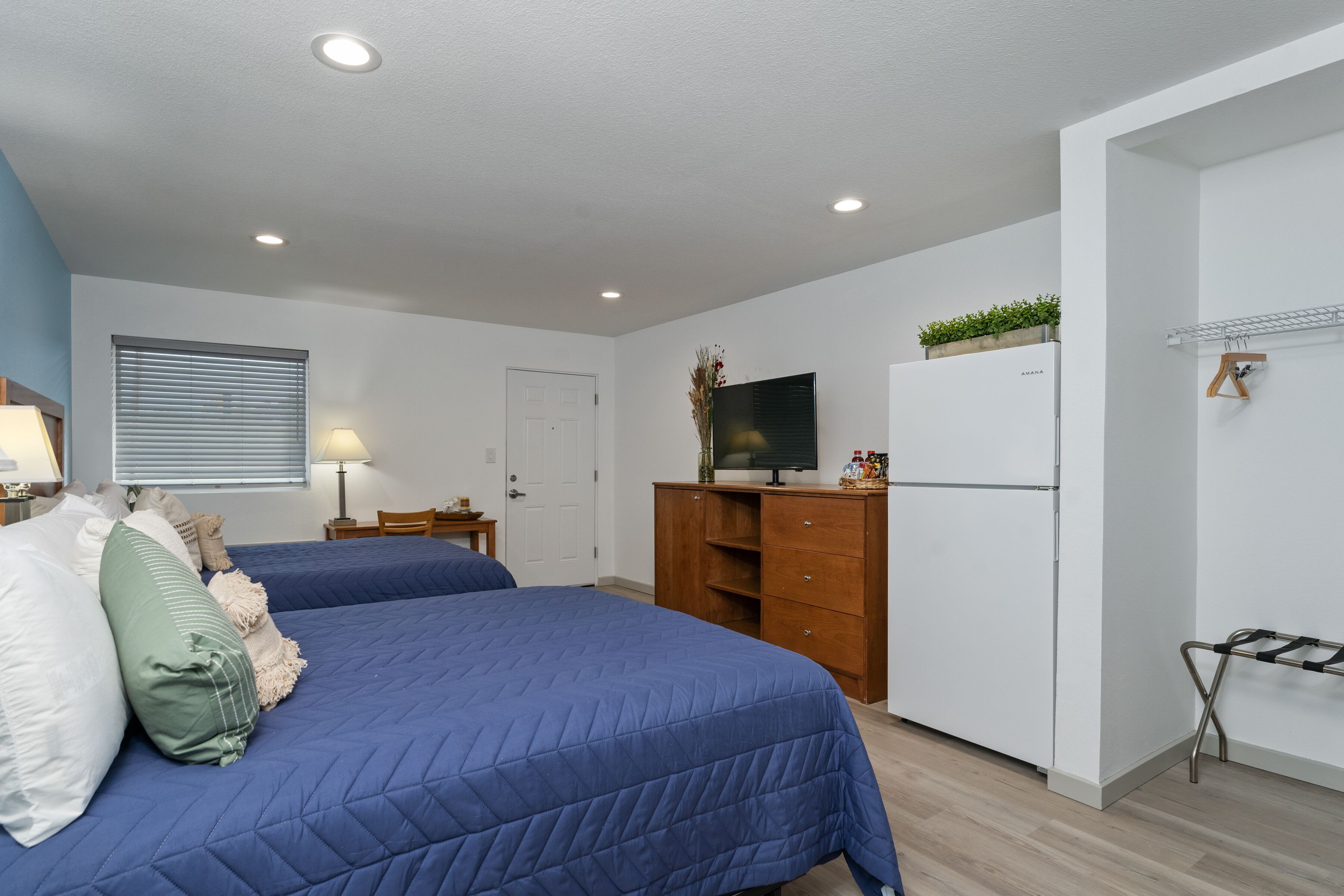 A bedroom with two beds, a TV, a wardrobe, and a small desk.