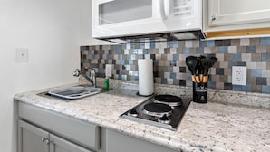 Una cocina con encimera de granito, microondas, estufa y salpicadero de azulejos.