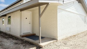 Una casa de un piso con un porche cubierto, una puerta principal y un pequeño jardín delantero.