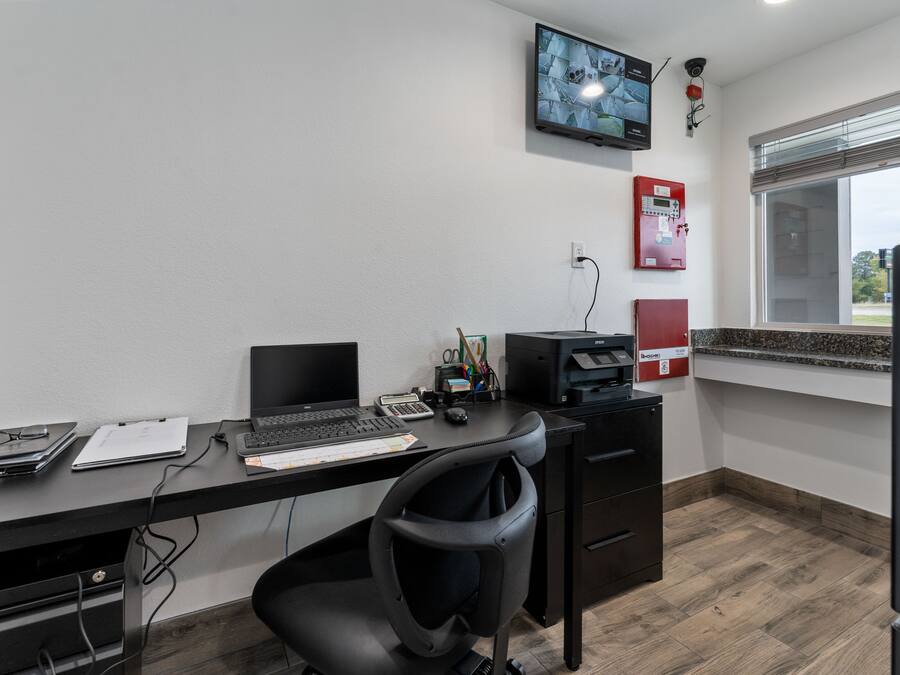 A modern office with a desk, chair, computer, and a mounted television.