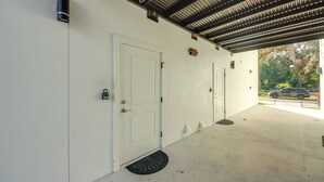 A covered parking area with two white doors, a metal roof, and a visible street with cars. - LaBelle Apartment, Close to Parks! (LaBelle)