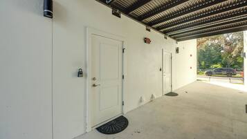 A covered parking area with two white doors, a metal roof, and a visible street with cars.
