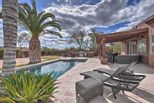 A poolside area with lounge chairs, a pergola, and a palm tree.