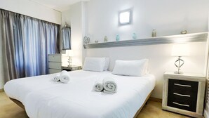 A hotel room with a large bed, white linens, a nightstand with a lamp, and a dresser with drawers. - Central Two Bedroom Apartment on the Second Line of the Beach in Marbella. (Marbella)